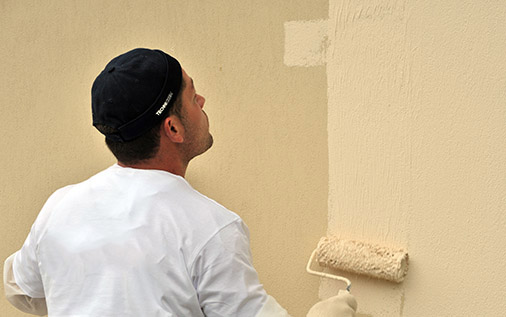 Homme qui applique la peinture sur mur extérieur